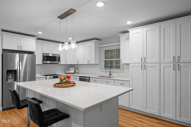 5208 Melbourne Rd, Raleigh, NC 27606 - kitchen with stainless steel appliances, a sink, a kitchen island, white cabinetry, and recessed lighting