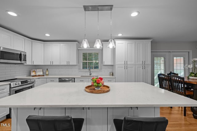 5208 Melbourne Rd, Raleigh, NC 27606 - kitchen with appliances with stainless steel finishes, a sink, a kitchen breakfast bar, decorative backsplash, and white cabinetry