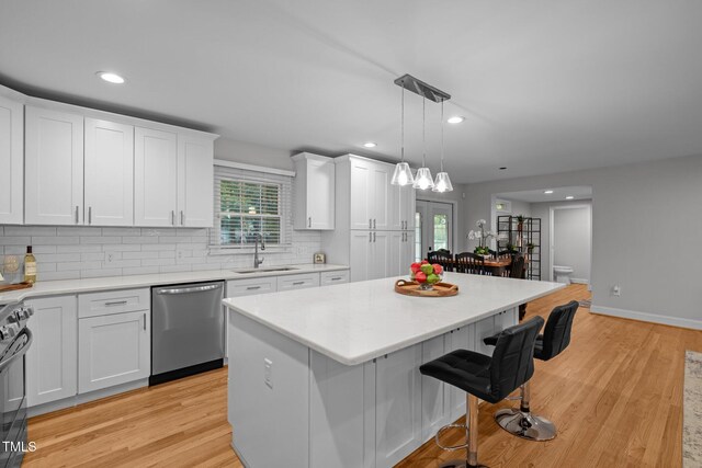 5208 Melbourne Rd, Raleigh, NC 27606 - kitchen with stainless steel dishwasher, a sink, a center island, a breakfast bar, and white cabinetry
