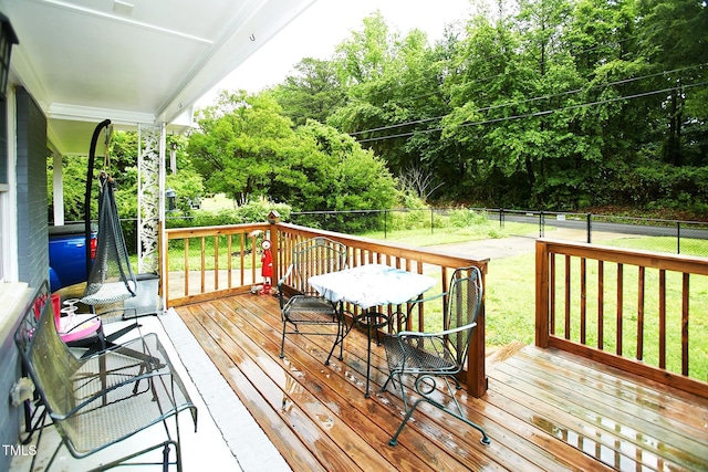 wooden deck with outdoor dining area and view of scattered trees