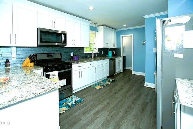 kitchen featuring appliances with stainless steel finishes, white cabinetry, decorative backsplash, crown molding, and baseboards