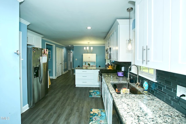 kitchen featuring appliances with stainless steel finishes, a chandelier, a sink, white cabinets, and backsplash