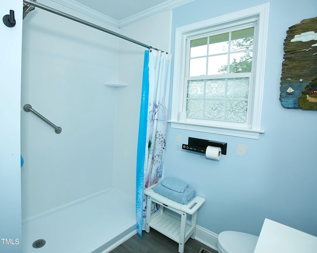 bathroom with ornamental molding, a shower with curtain, toilet, wood finished floors, and baseboards