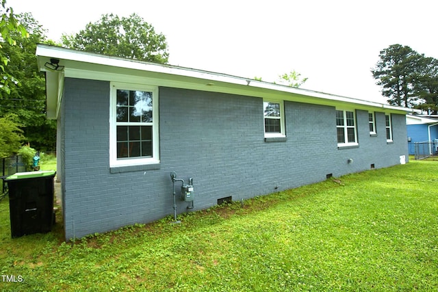 view of side of home with brick siding, a lawn, and crawl space