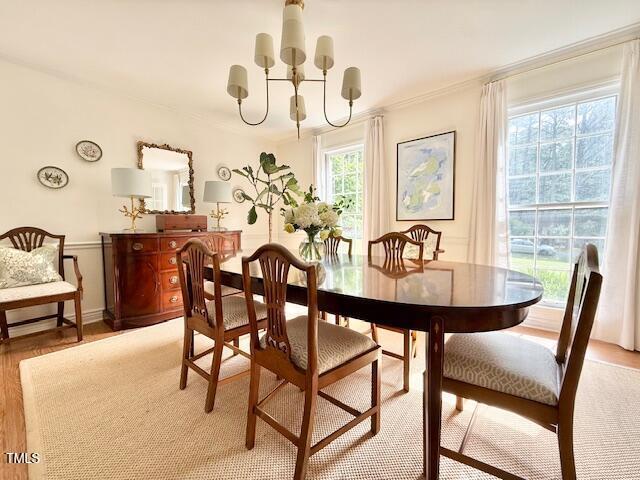 dining space with a chandelier, light wood-style flooring, and ornamental molding