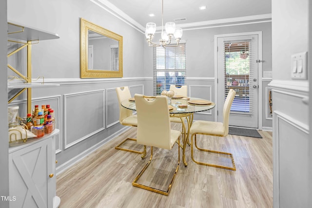 dining space with a decorative wall, crown molding, a wainscoted wall, wood finished floors, and a chandelier