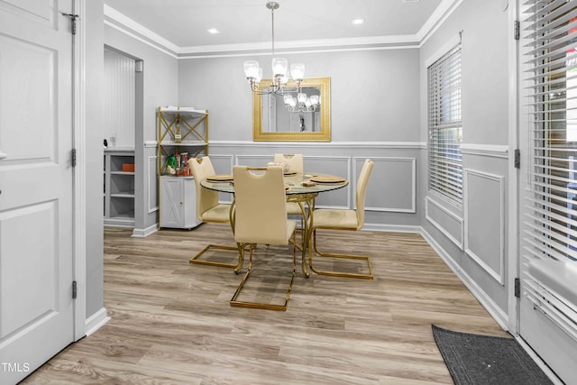 dining room featuring ornamental molding, a chandelier, wood finished floors, a decorative wall, and a wainscoted wall
