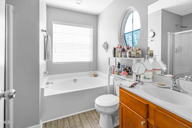 bathroom featuring a shower stall, wood finished floors, toilet, a garden tub, and vanity