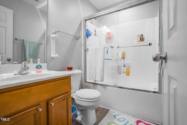 full bath with enclosed tub / shower combo, toilet, vanity, and wood finished floors