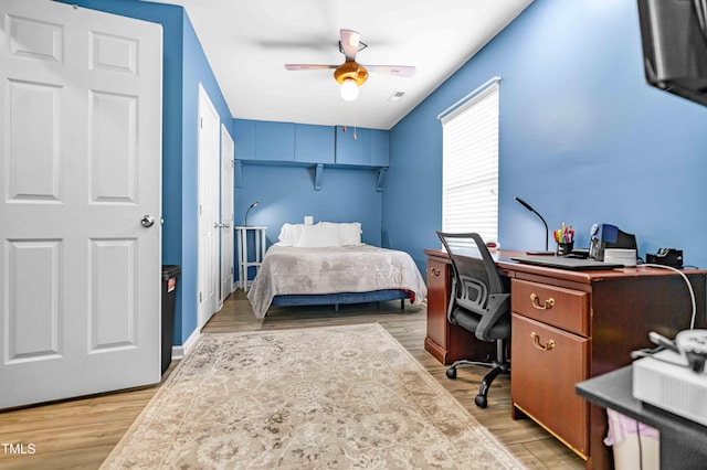 bedroom featuring an office area, light wood finished floors, and ceiling fan