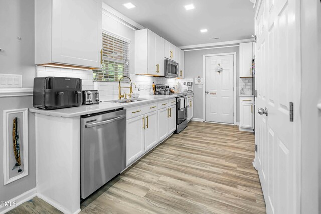 kitchen featuring appliances with stainless steel finishes, a sink, white cabinets, and light countertops