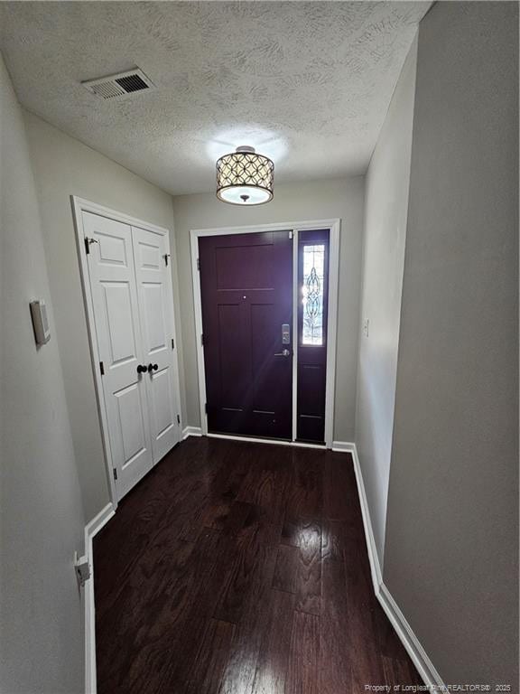 5472 Robmont Dr, Fayetteville, NC 28306 - doorway featuring a textured ceiling, baseboards, dark wood-style floors, and visible vents