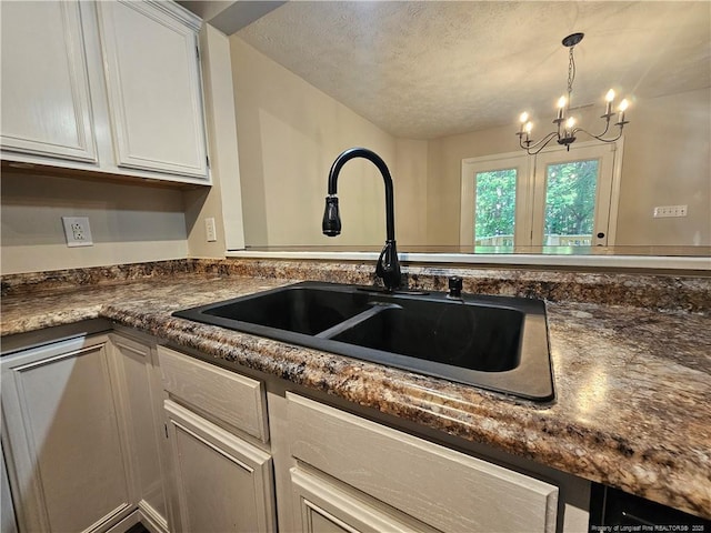 5472 Robmont Dr, Fayetteville, NC 28306 - kitchen with a sink, a textured ceiling, an inviting chandelier, white cabinetry, and dark countertops