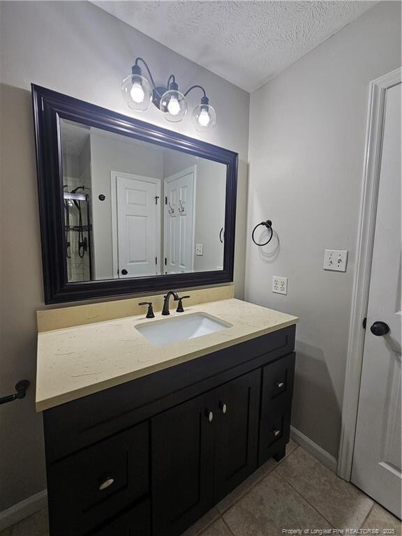 5472 Robmont Dr, Fayetteville, NC 28306 - bathroom featuring vanity, a textured ceiling, baseboards, and tile patterned floors