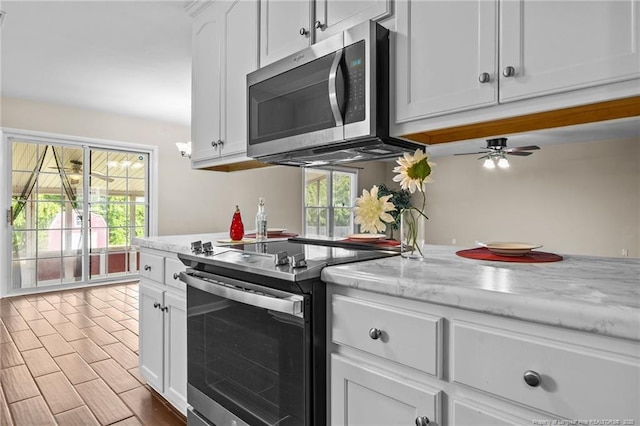 6750 Weeping Water Run, Fayetteville, NC 28314 - kitchen featuring white cabinets, stainless steel appliances, light stone countertops, and a ceiling fan