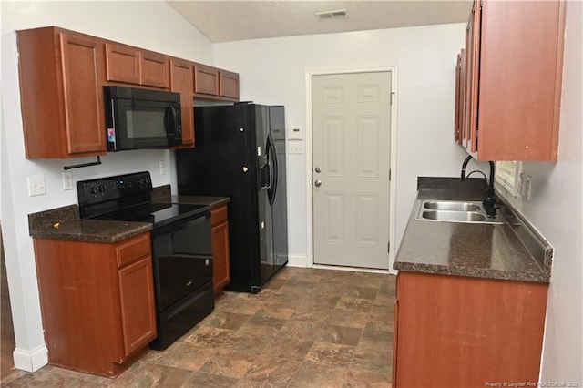 kitchen with black appliances, a sink, dark countertops, stone finish flooring, and baseboards