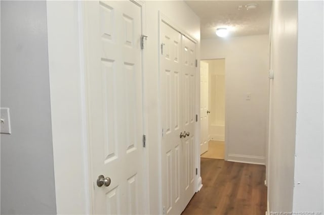 hallway featuring dark wood finished floors and baseboards