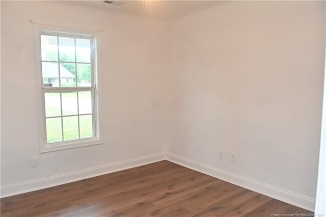 unfurnished room with baseboards and dark wood-type flooring