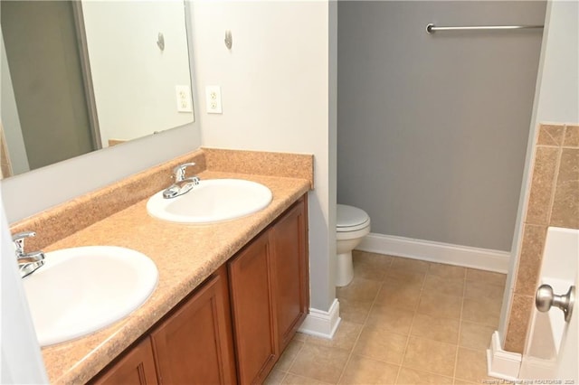 bathroom featuring toilet, tile patterned floors, double vanity, and baseboards