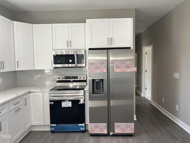kitchen with appliances with stainless steel finishes, dark wood-style floors, white cabinetry, and light stone countertops