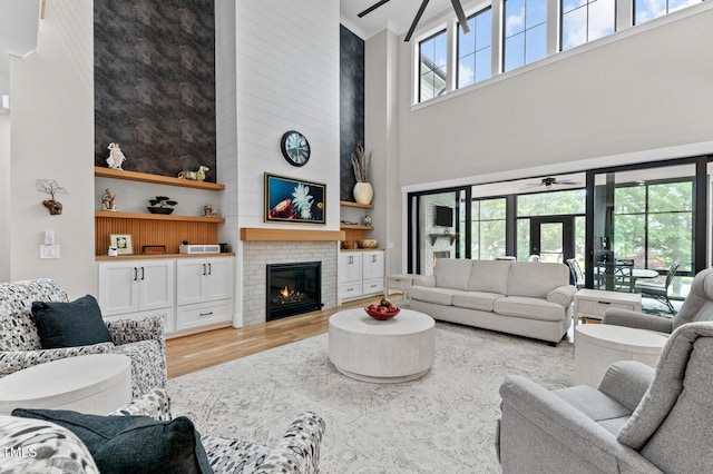 1229 Perry Bluff Dr, Wake Forest, NC 27587 - living room featuring a towering ceiling, a ceiling fan, light wood-type flooring, a fireplace, and french doors