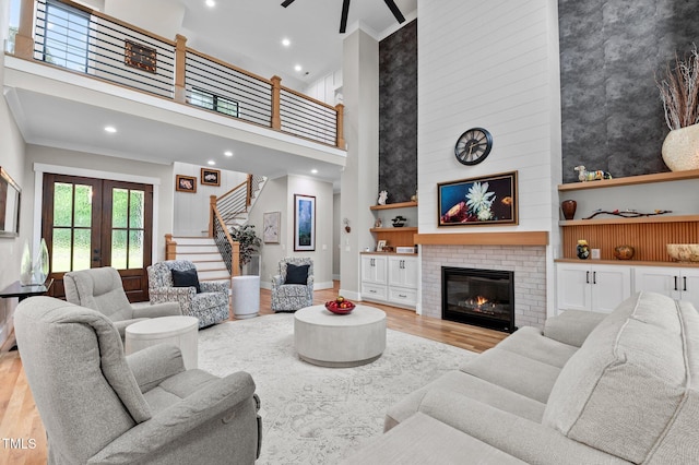 1229 Perry Bluff Dr, Wake Forest, NC 27587 - living room featuring light wood-style floors, a towering ceiling, a large fireplace, french doors, and stairs