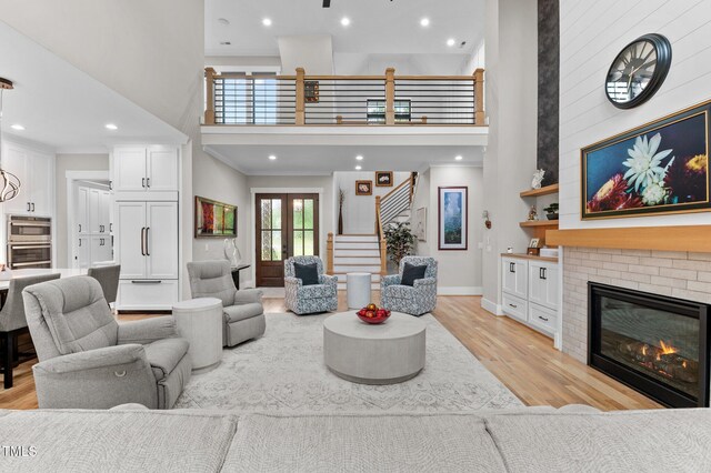 1229 Perry Bluff Dr, Wake Forest, NC 27587 - living room featuring a towering ceiling, light wood finished floors, a brick fireplace, baseboards, and stairway