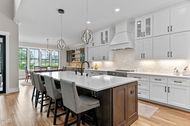 1229 Perry Bluff Dr, Wake Forest, NC 27587 - kitchen with custom exhaust hood, light countertops, backsplash, a sink, and a breakfast bar area