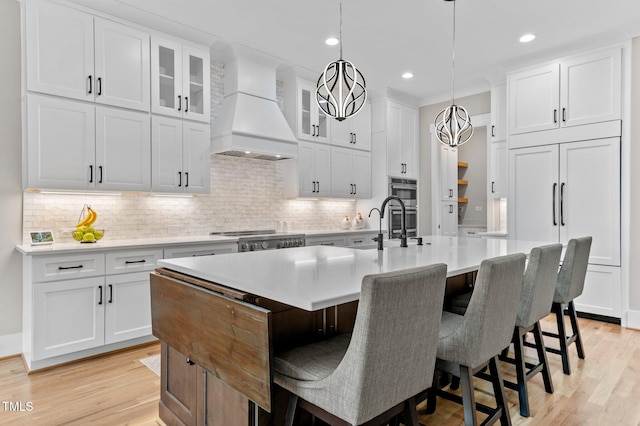 1229 Perry Bluff Dr, Wake Forest, NC 27587 - kitchen featuring premium range hood, light wood-type flooring, a center island with sink, light countertops, and recessed lighting