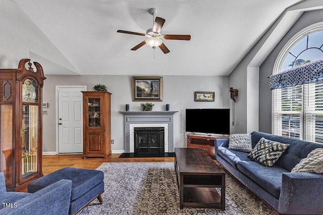 living room featuring ceiling fan, a fireplace with flush hearth, wood finished floors, and high vaulted ceiling
