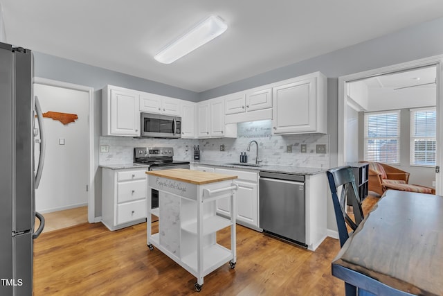 kitchen featuring appliances with stainless steel finishes, a sink, wooden counters, open shelves, and tasteful backsplash