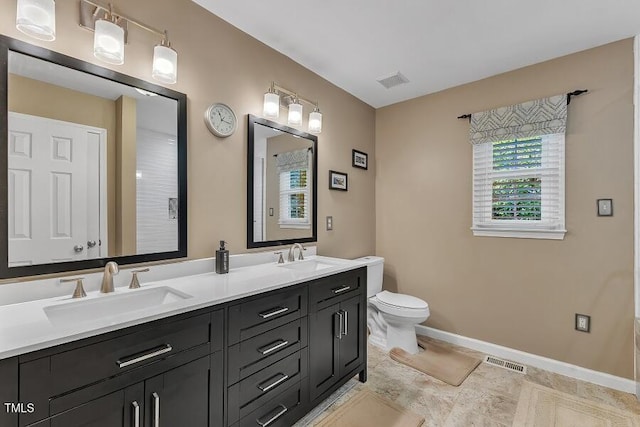 bathroom with baseboards, toilet, and double vanity