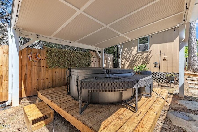 wooden terrace with a hot tub and fence