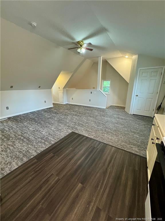 bonus room featuring lofted ceiling, dark wood finished floors, a ceiling fan, baseboards, and dark carpet