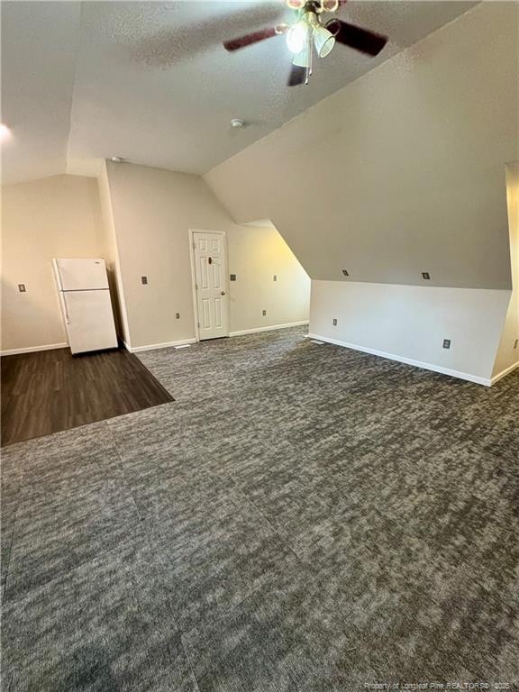 bonus room with lofted ceiling, a textured ceiling, carpet, baseboards, and ceiling fan