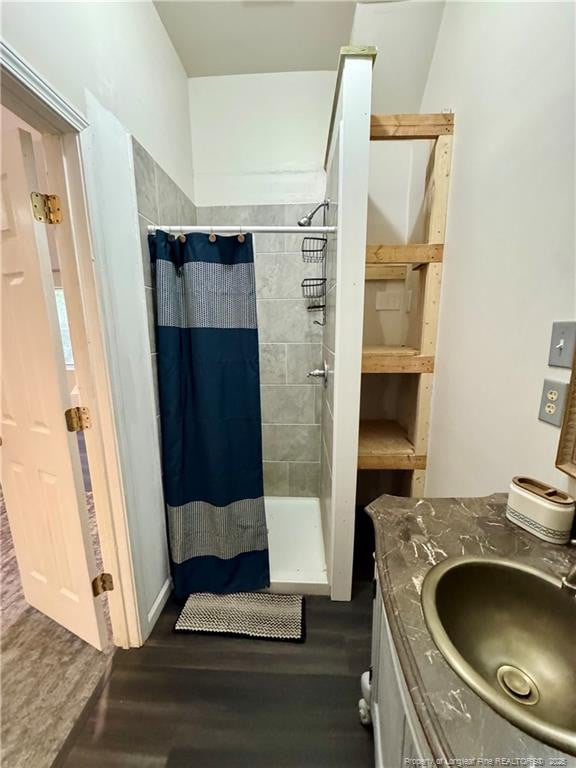 full bath with vanity, a shower stall, and wood finished floors