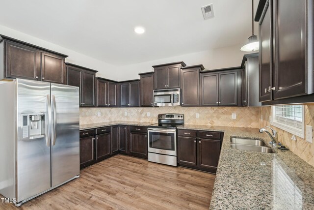 265 Wind Swept St, Raeford, NC 28376 - kitchen featuring stainless steel appliances, a sink, dark brown cabinets, light stone counters, and light wood finished floors