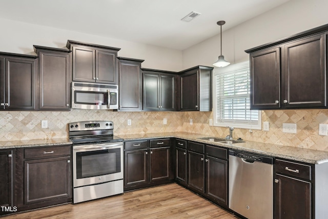 265 Wind Swept St, Raeford, NC 28376 - kitchen featuring stainless steel appliances, a sink, light stone counters, light wood-style flooring, and decorative light fixtures