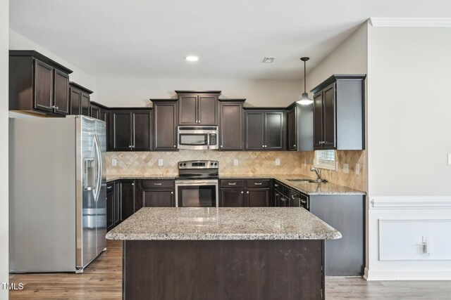 265 Wind Swept St, Raeford, NC 28376 - kitchen with stainless steel appliances, dark brown cabinetry, a kitchen island, light stone counters, and a sink