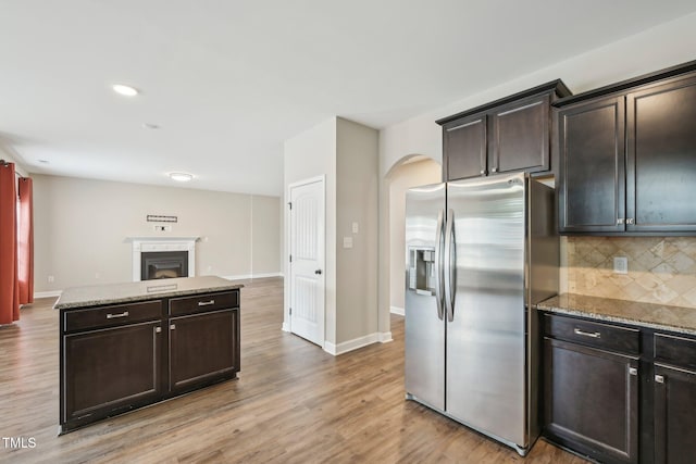 265 Wind Swept St, Raeford, NC 28376 - kitchen with stainless steel fridge, arched walkways, tasteful backsplash, light wood-type flooring, and open floor plan