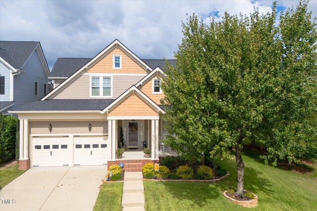 view of front of home with driveway, a front yard, a garage, covered porch, and roof with shingles