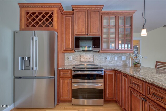 kitchen with stainless steel appliances, brown cabinetry, light stone countertops, and backsplash