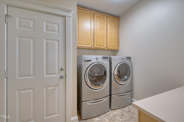 washroom with cabinet space, washer and clothes dryer, and baseboards