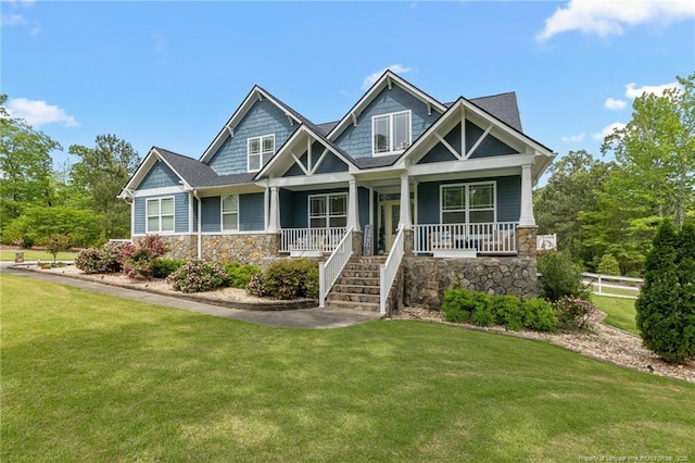 craftsman house with stone siding, a porch, and a front lawn