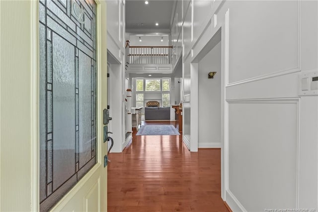 hallway with wood finished floors and a towering ceiling