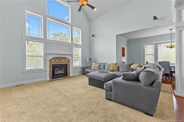 carpeted living area with a ceiling fan, baseboards, a fireplace, and high vaulted ceiling