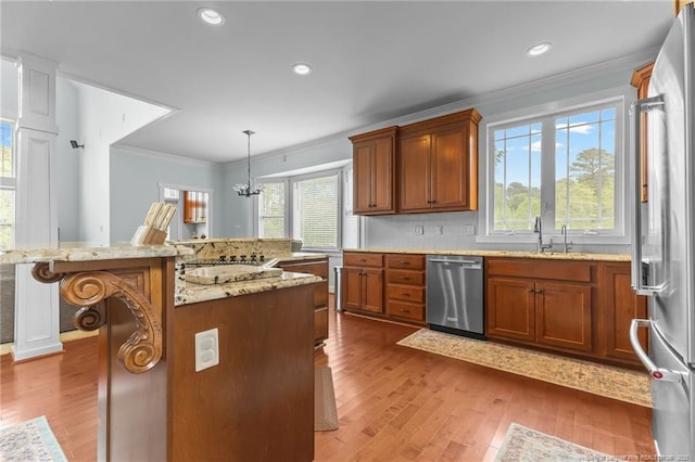 kitchen featuring a sink, ornamental molding, wood finished floors, and appliances with stainless steel finishes