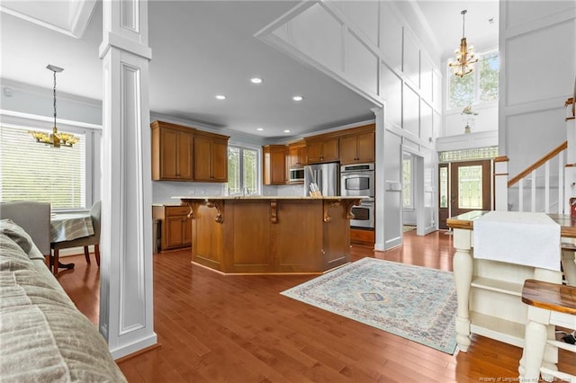 kitchen featuring crown molding, brown cabinets, a notable chandelier, and appliances with stainless steel finishes