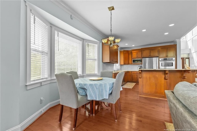 dining space with a chandelier, wood finished floors, ornamental molding, and recessed lighting