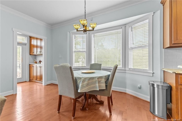 dining space featuring light wood finished floors, a healthy amount of sunlight, a chandelier, and crown molding